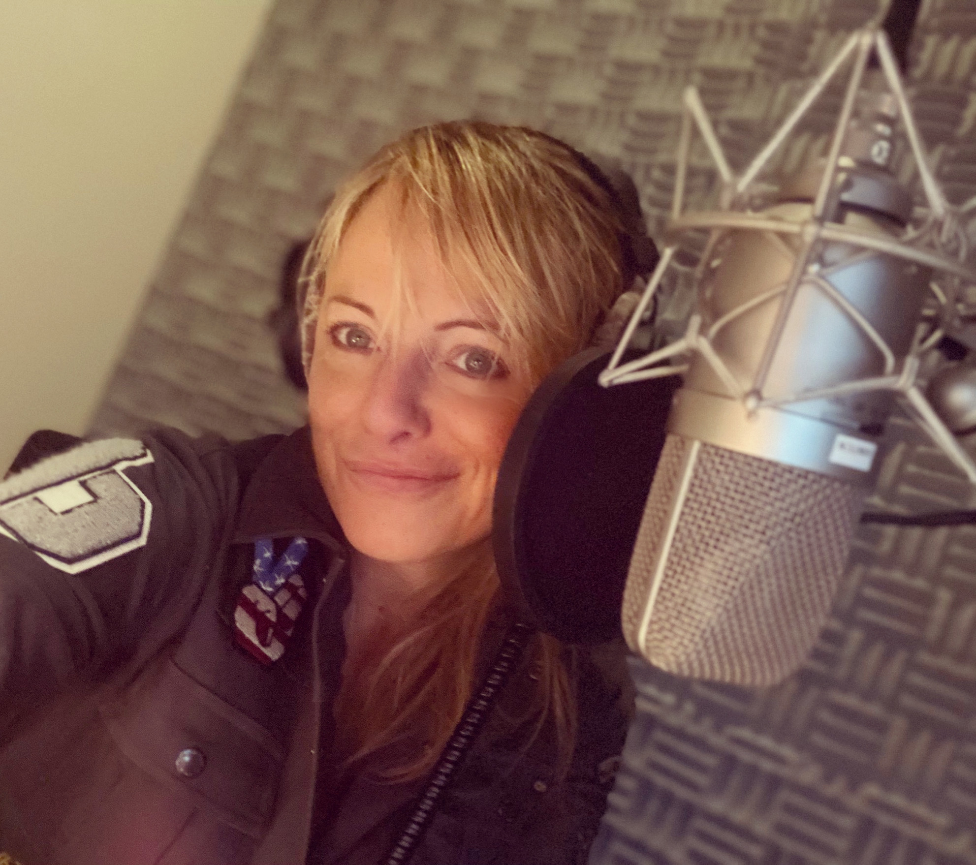 Jo Kern wearing headphones next to a large studio microphone