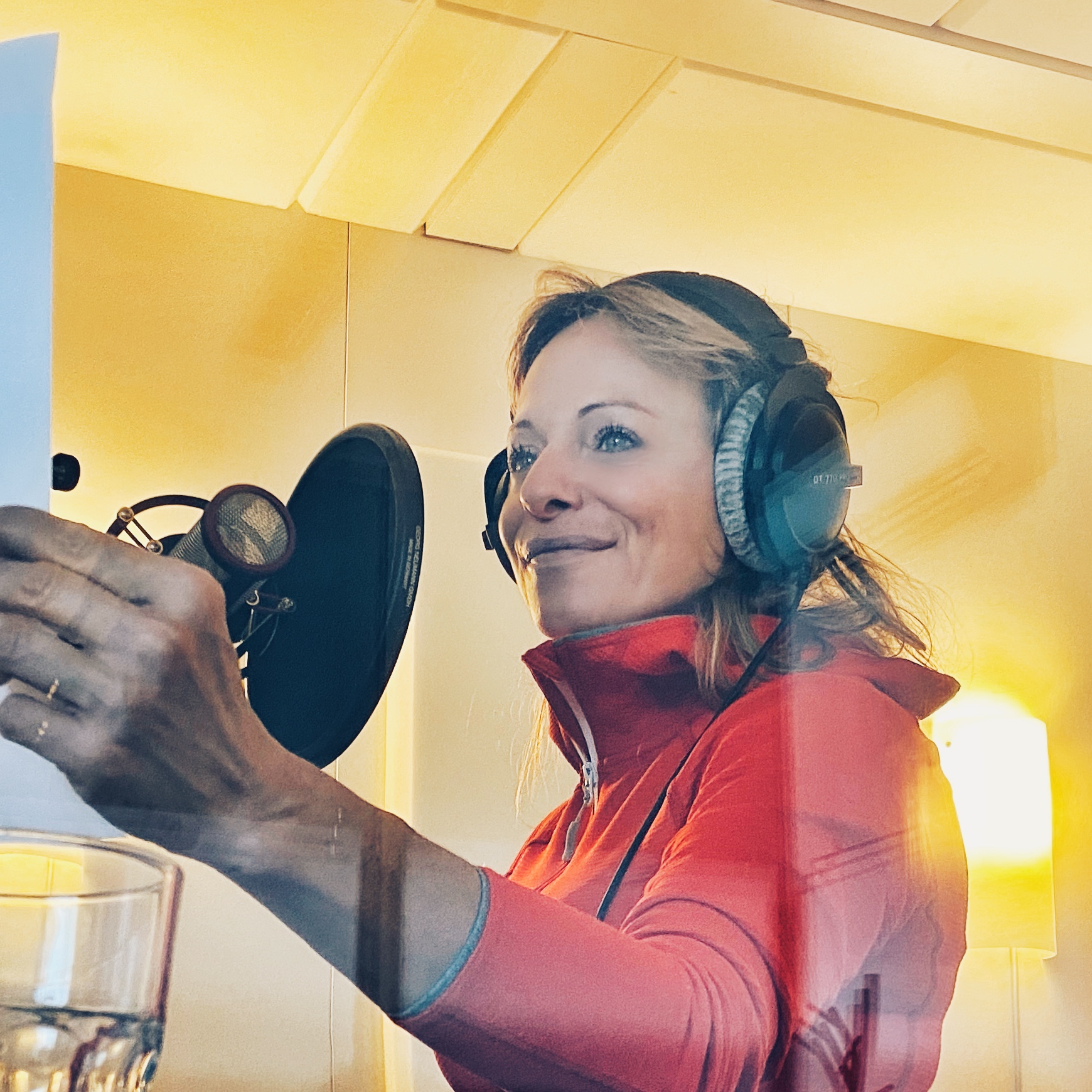 Jo Kern in a red top at the microphone with a pop filter